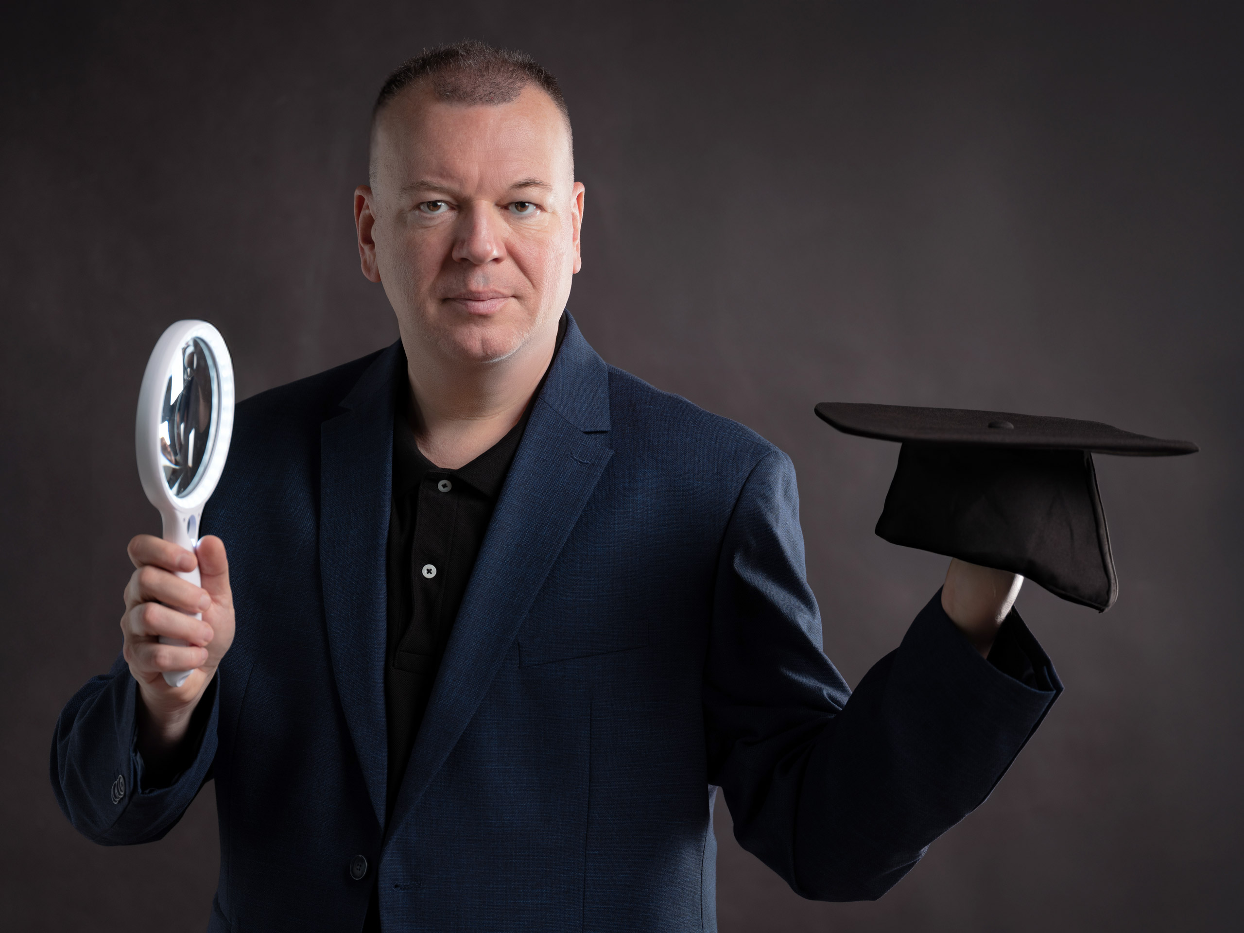 vergrößern Stefan Weber präsentiert Leselupe und Doktorhut