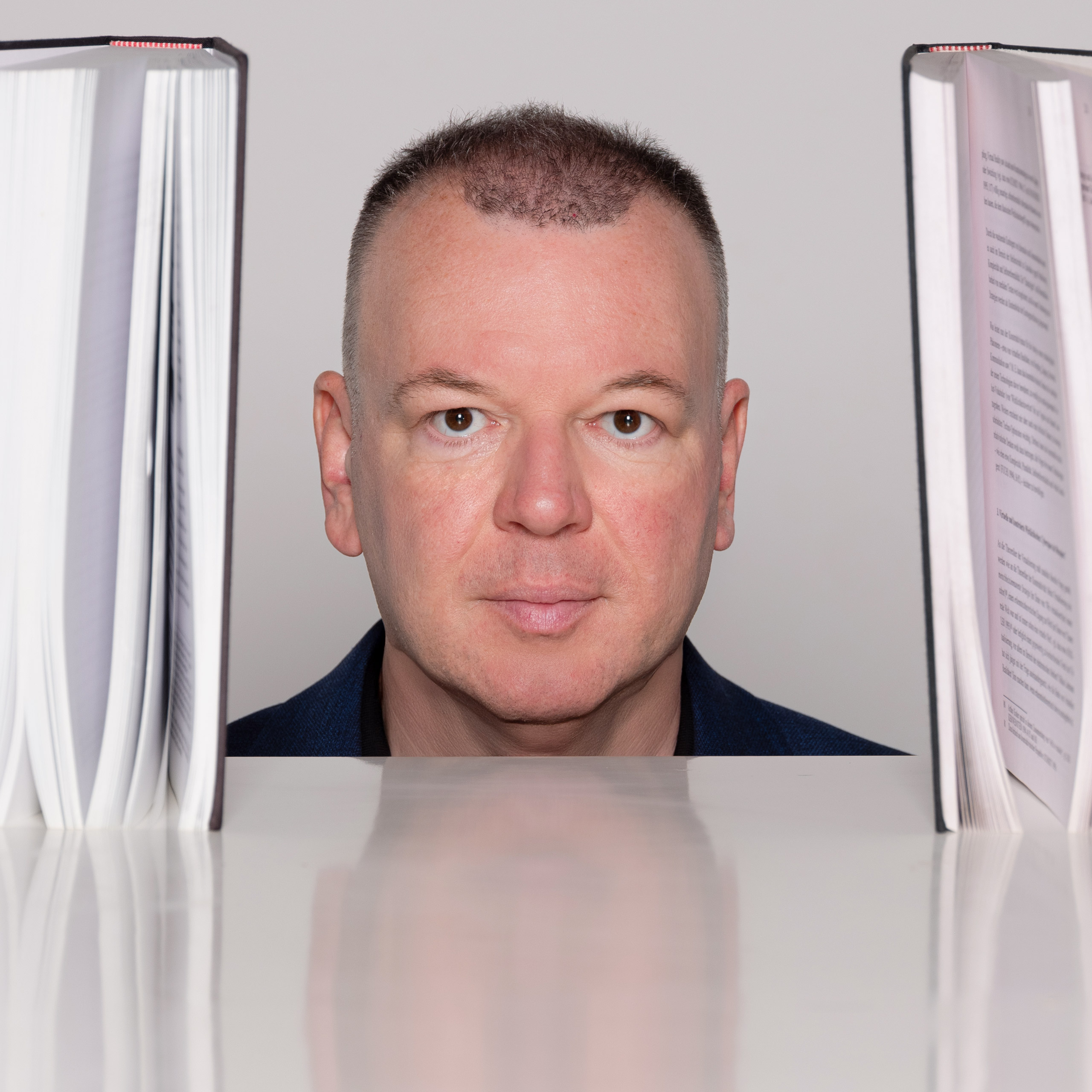 vergrößern Stefan Weber zwischen offenen Büchern